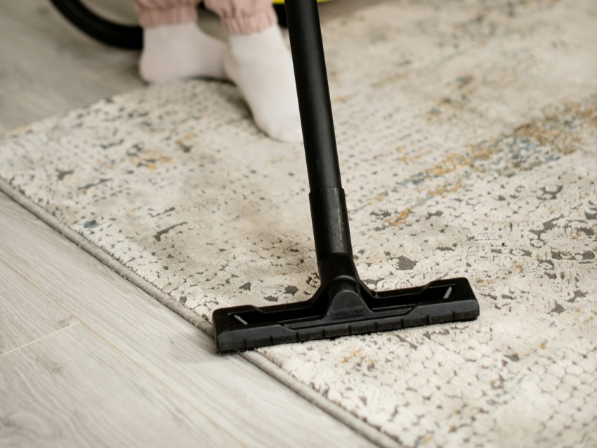 Vacuuming beige patterned area rug